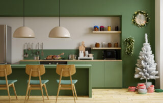 Modern kitchen with fern green cabinets decorated for the holidays, featuring a white Christmas tree, festive wreaths, and holiday decor on the countertop.